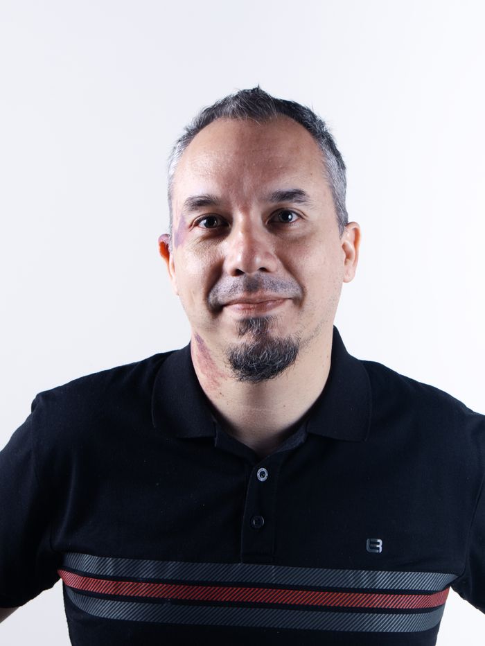 Casual portrait of a man in a black polo shirt against a white background.