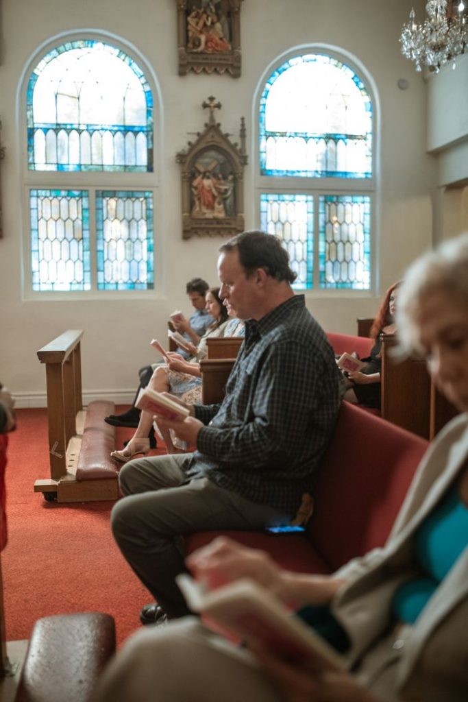 Indoor church scene with parishioners reading hymn books during service.